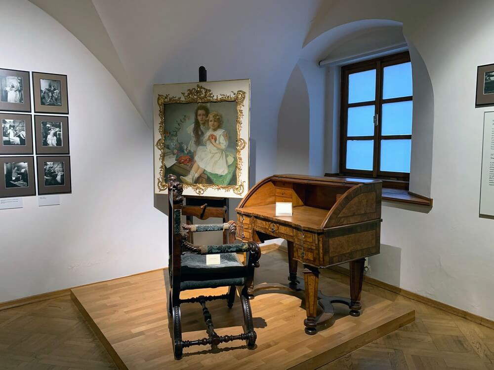 Mucha Museum: A wooden desk in a room with photos on the walls 