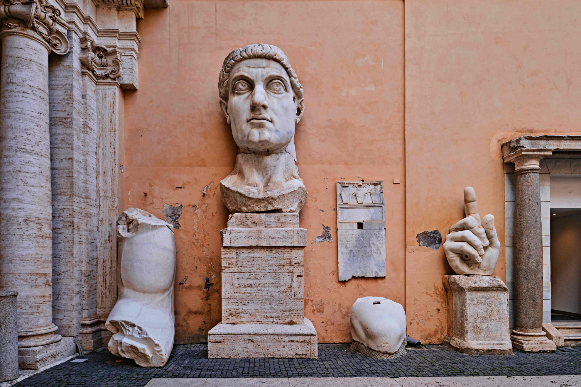 Museums in Rome: Red wall with stone statues of a male bust resting against it