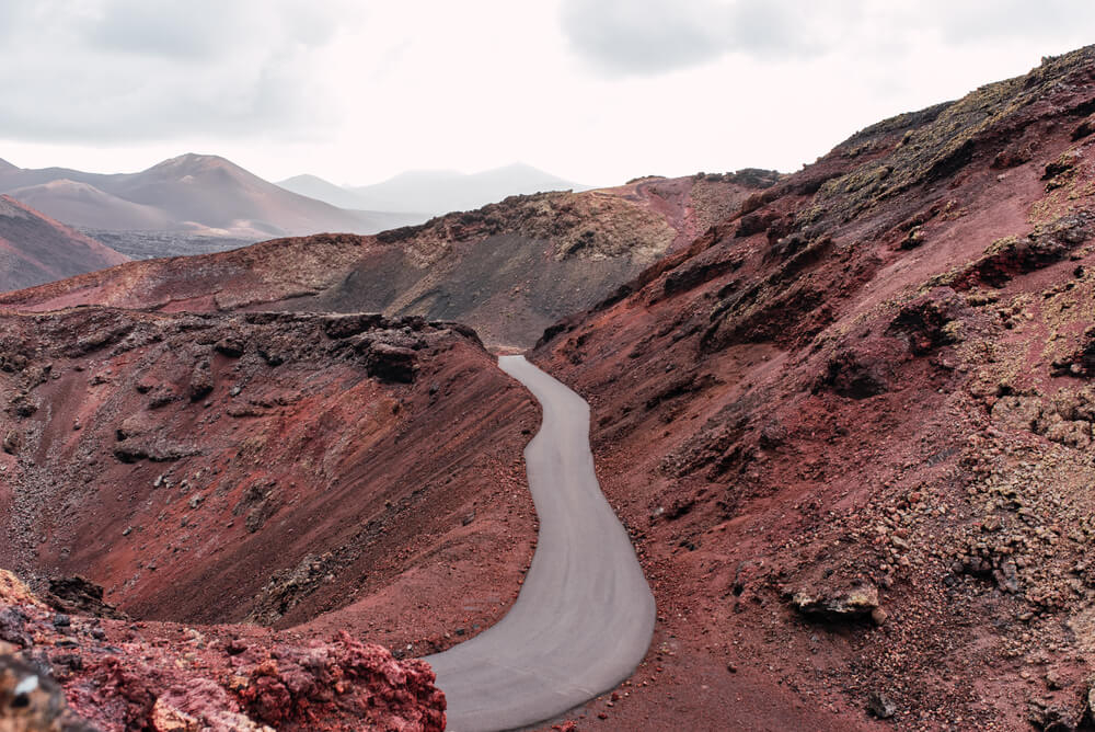 Straße in einer roten Vulkanlandschaft im Nationalpark Timanfaya auf Lanzarote. 