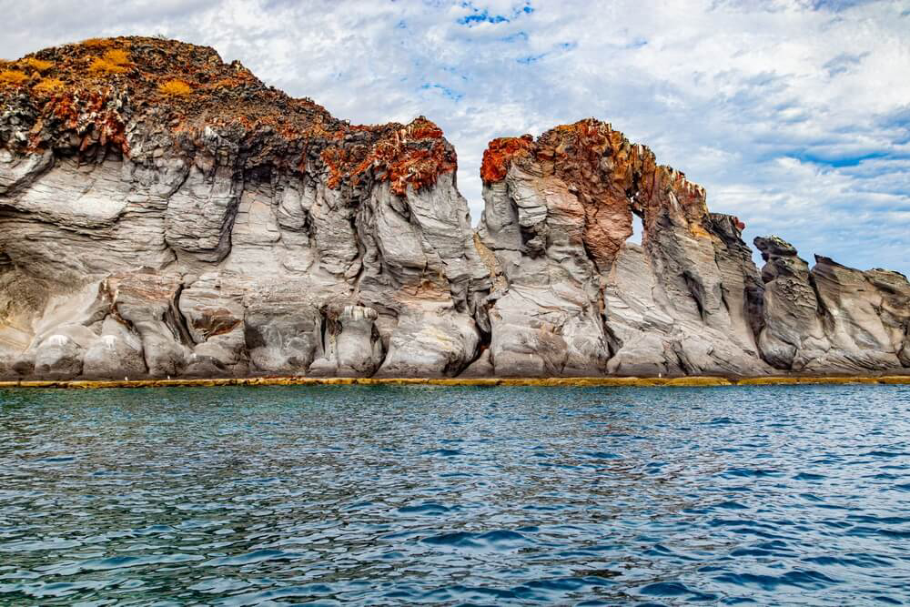      Natur in Mexiko: mit roten Pflanzen bewachsene Klippen im Nationalpark Bahía de Loreto