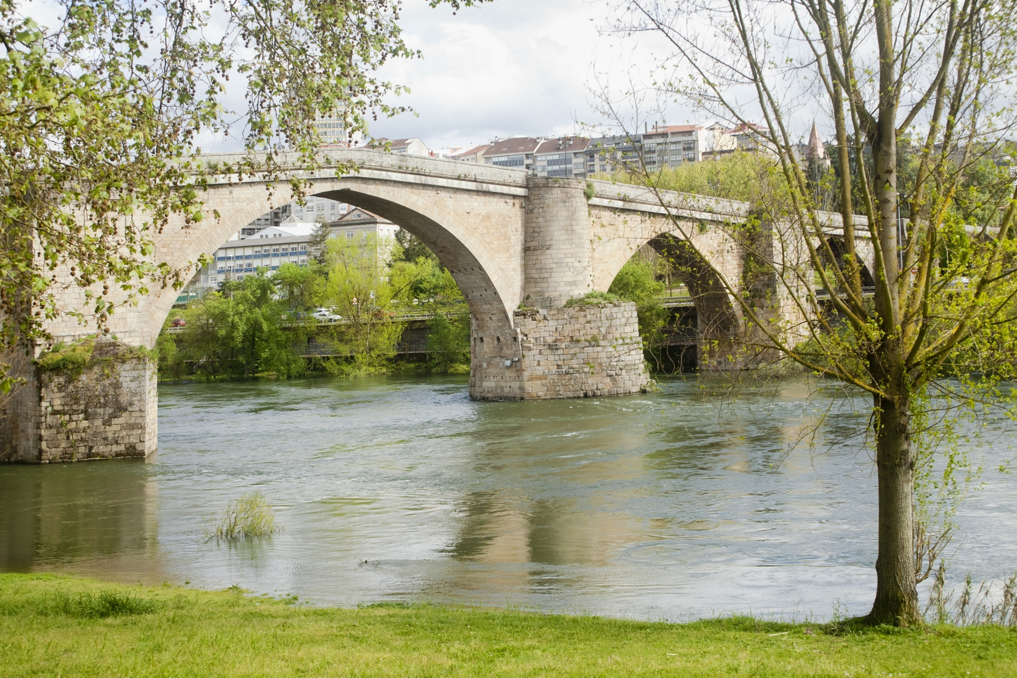 Side view of ancient stone arch bridge in Ourense, Galicia, Spain over river Miño.