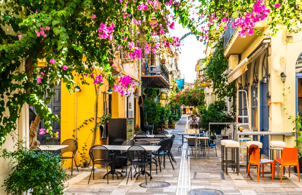 Nafpilo: A pedestrian street with yellow buildings and tables and chairs on the street