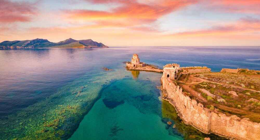 Peloponnese peninsula: Sun setting over the ocean with a fort in view