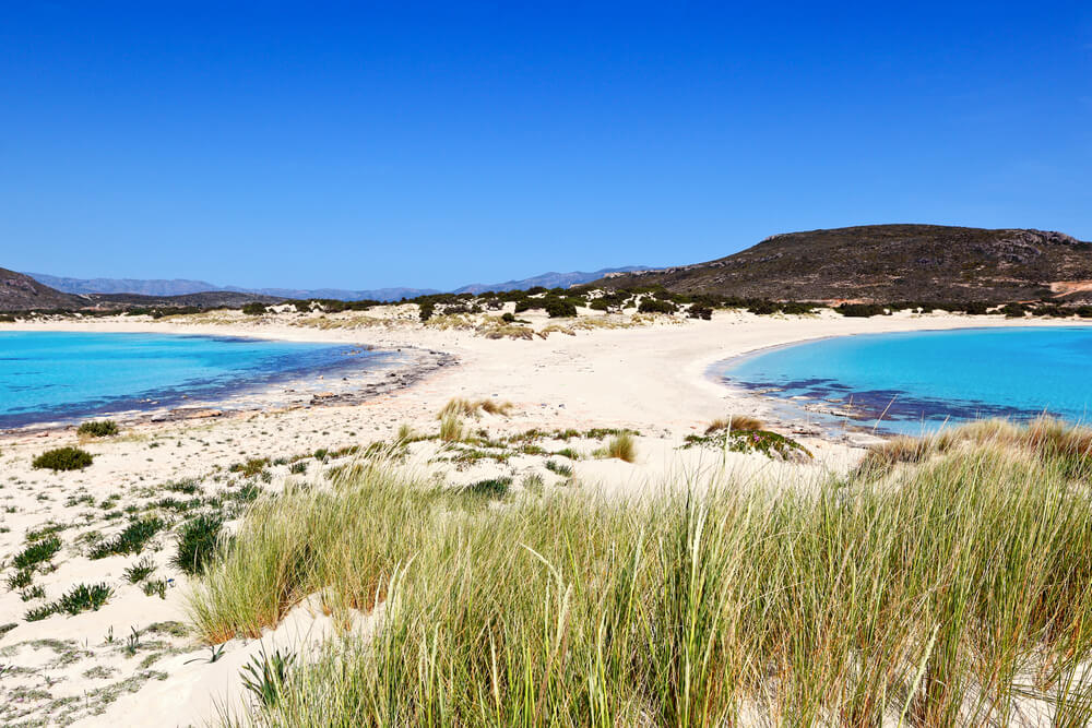 Simos Beach: White sand and topaz water with hills in the distance 