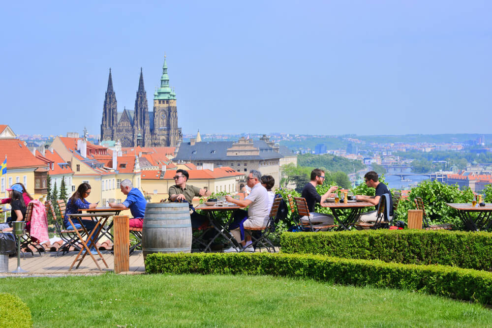 Menschen auf einer Terrasse mit Aussicht über die Stadt Prag.