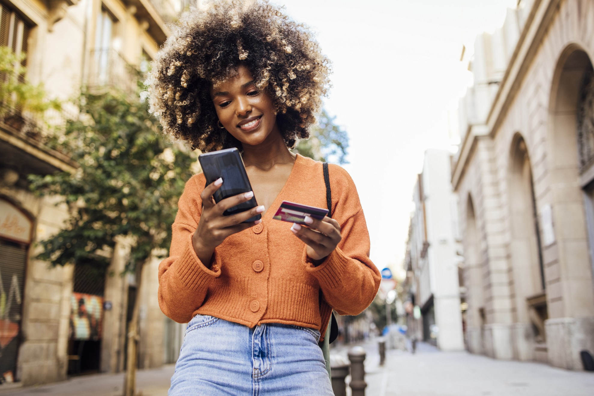 Portrait of a young African American woman on vacation in Barcelona shopping online on the street.