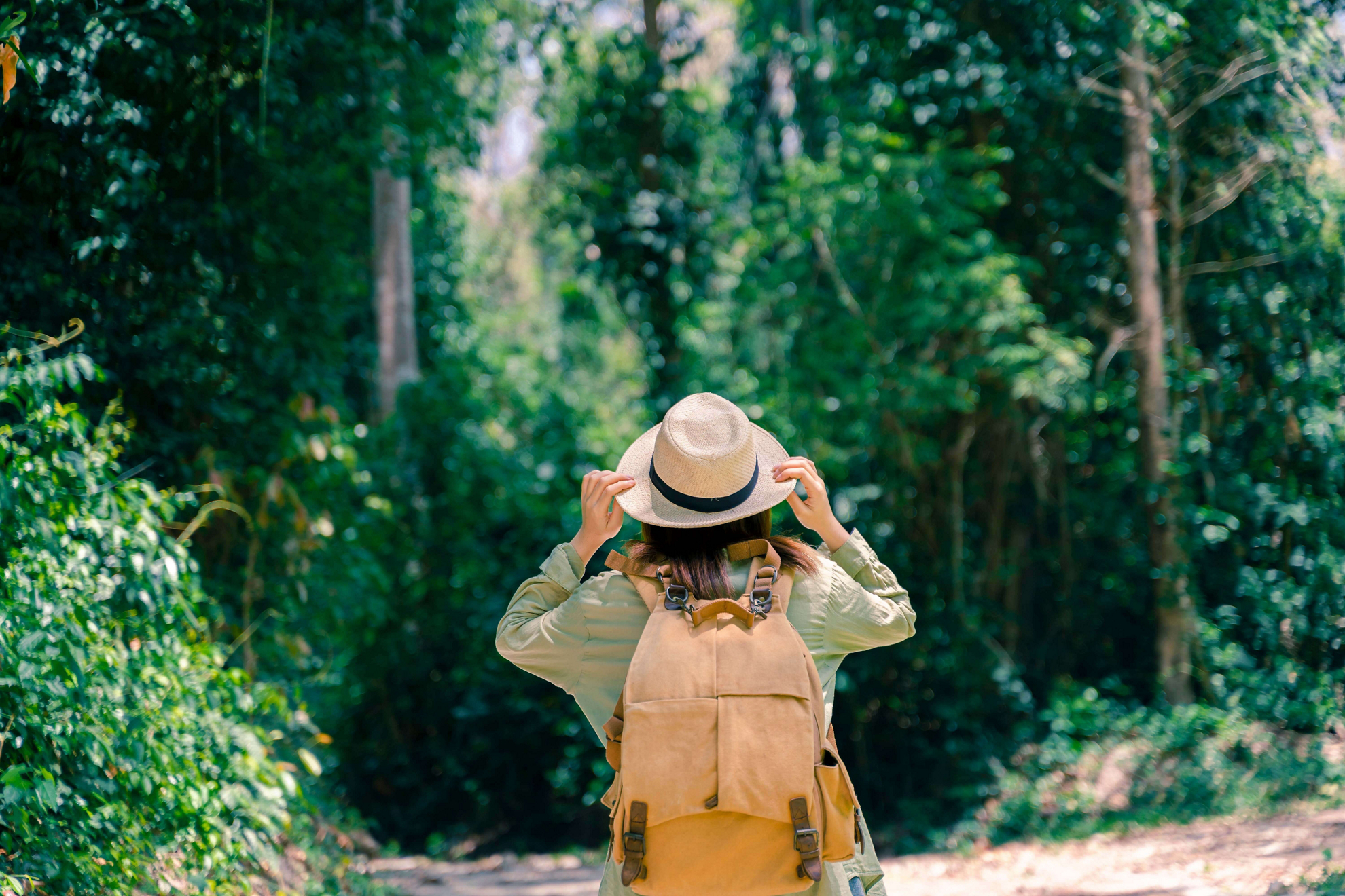 Regenerative tourism: Woman walking with a backpack in a forest