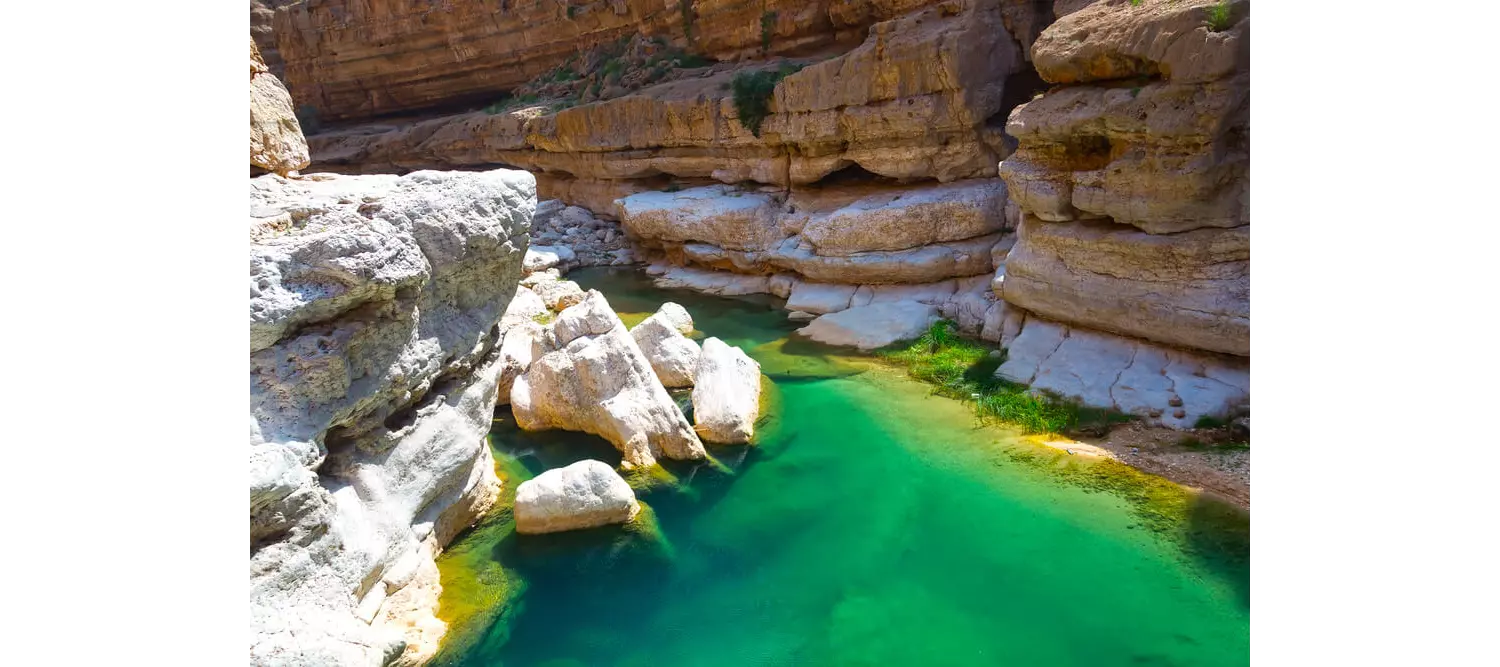 Reise in den Oman: wasserführender Wadi mit türkisblauem Wasser.