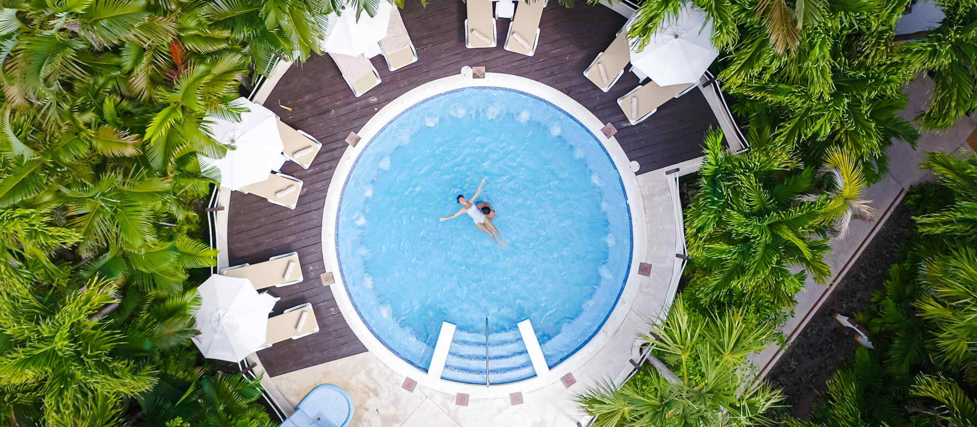 Flitterwochen-Urlaub: Paar in einem Whirlpool umgeben von tropischer Vegetation.