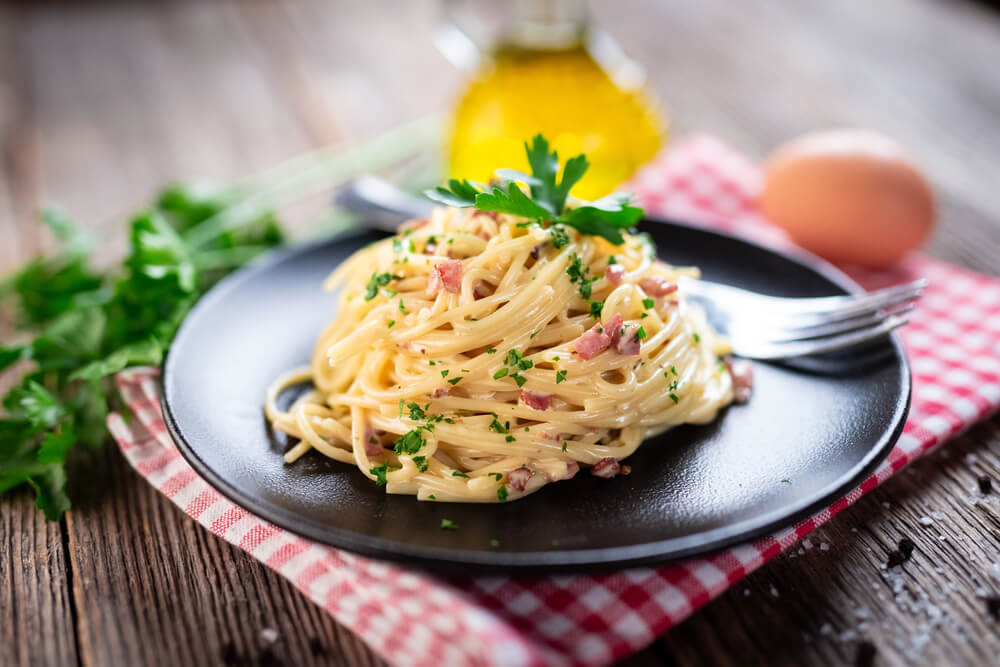 Roman cuisine: A plate of spaghetti alla carbonara on a red gingham cloth