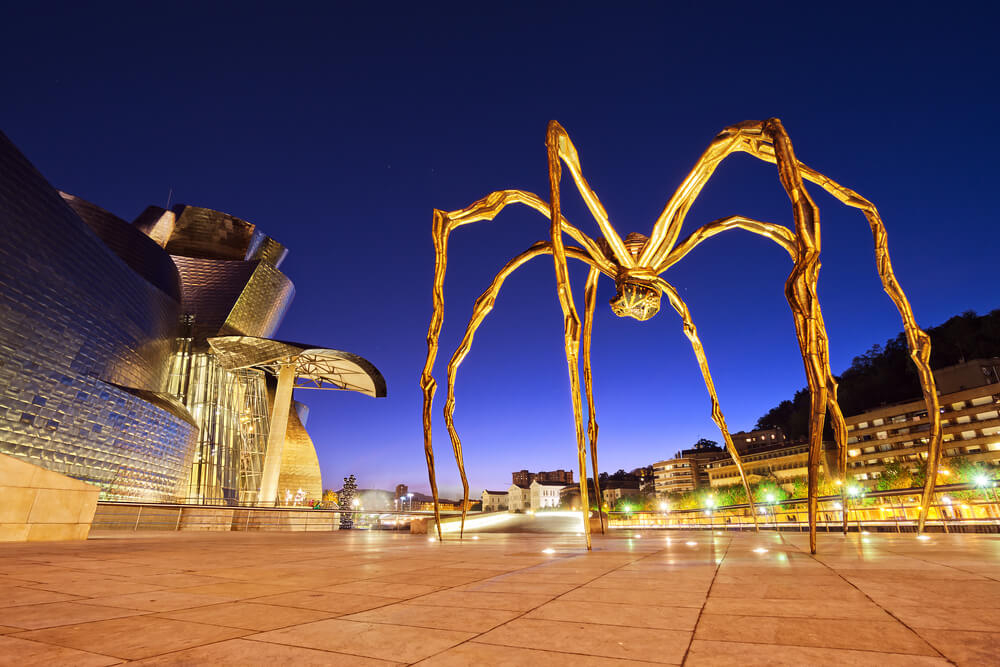 Romantic getaways in Spain: View of a spider sculpture and the Guggenheim Bilbao at night