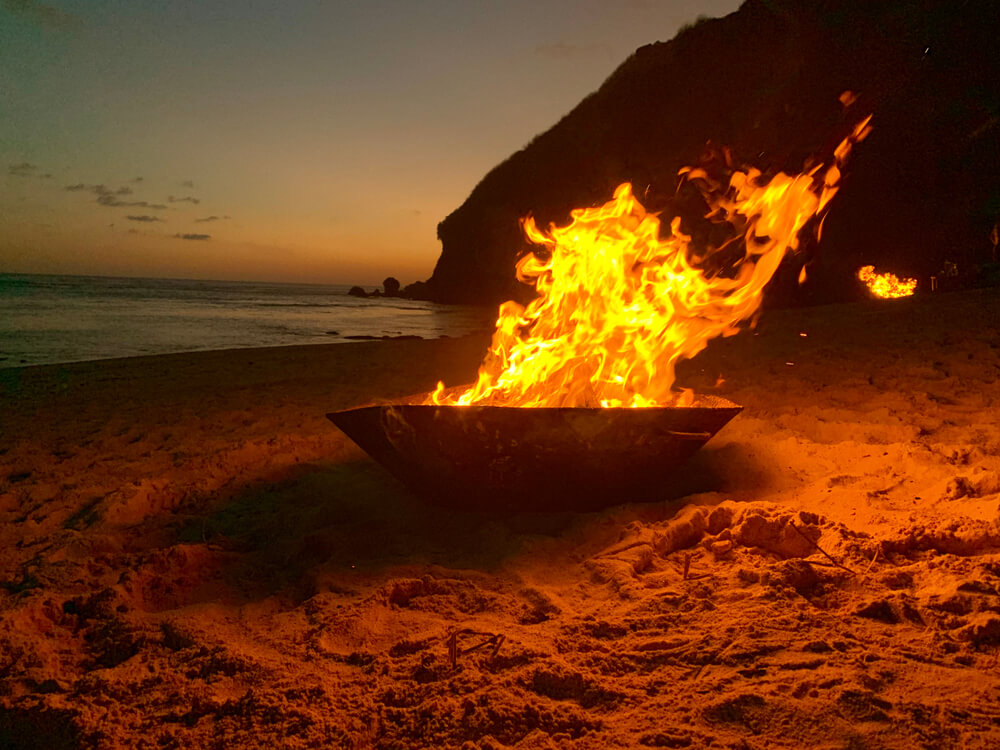 Two men jumping over a bonfire on the beach