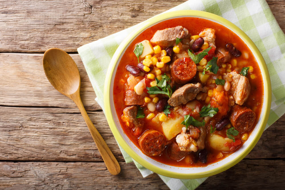 Cachupa: A close-up of a bowl of red stew with beans and meat