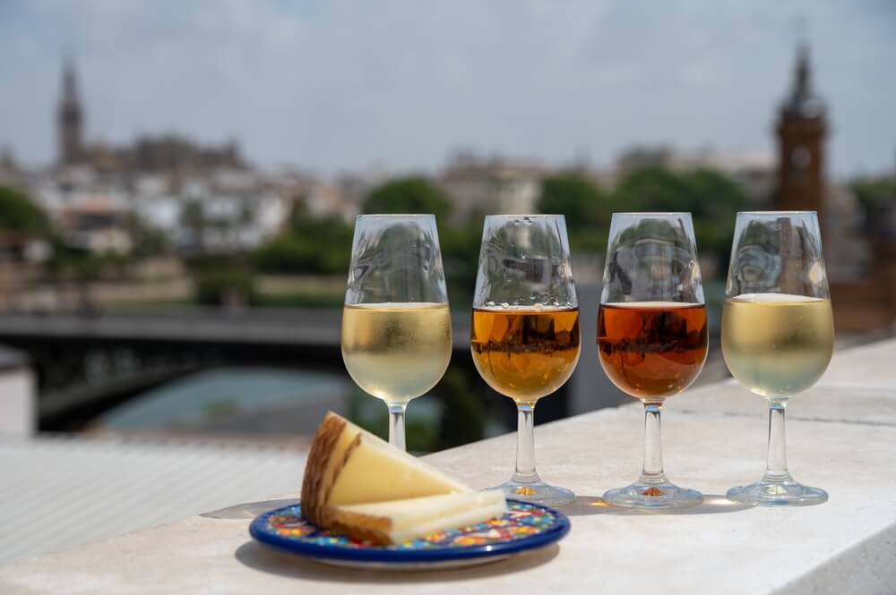 Sherry: Four full sherry glasses lined in a row with a plate of cheese