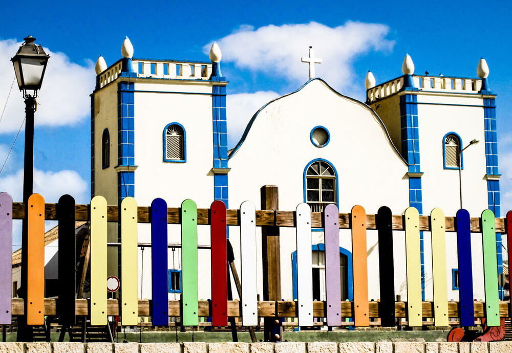 Boa Vista: A white house with blue tiles and details surrounded by a multicoloured fence