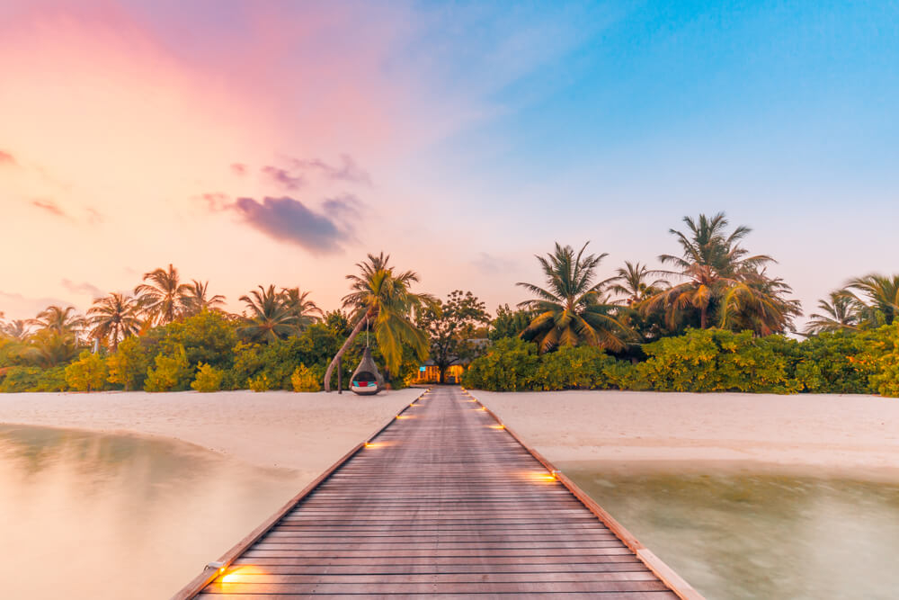 Slow Travel: A white sand beach in the Maldives bathed in pink light at sunset
