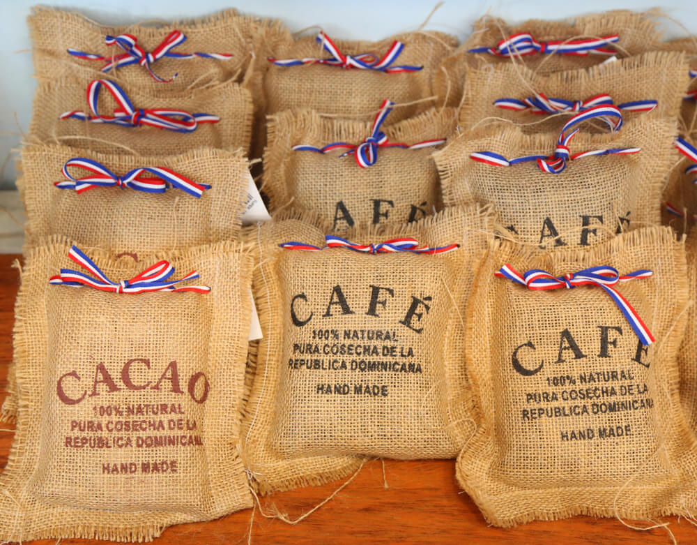 A bunch of Dominican coffee in straw sacks, tied in colorful ribbons, sit on a table