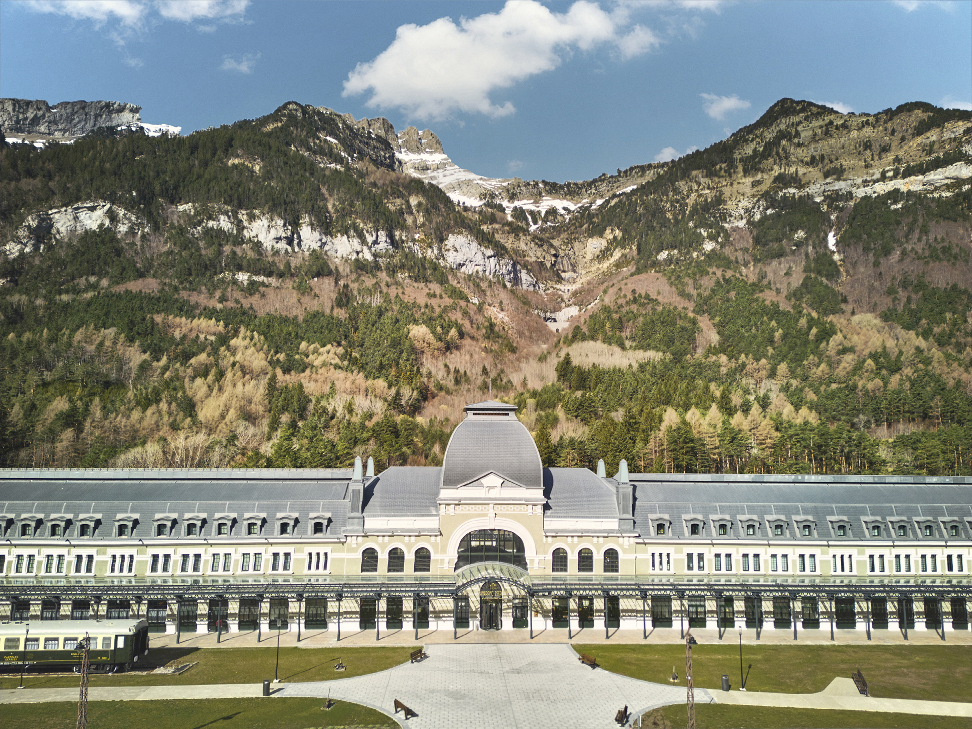 Spanische Pyrenäen: historisches Bahnhofsgebäude mit hohen Bergen im Hintergrund.