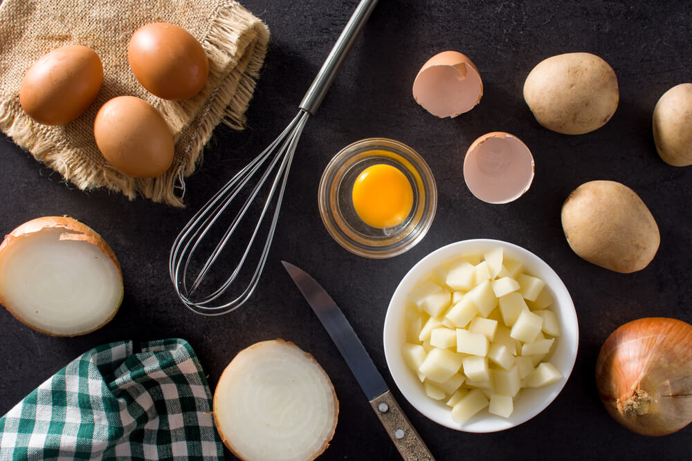 Zutaten und Utensilien für eine spanische Tortilla.