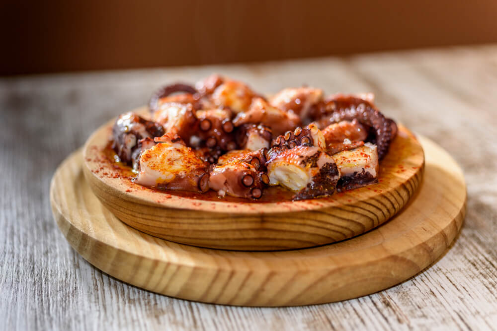 Pulpo a feira: A wooden plate of chopped octopus tapas covered in oil and paprika
