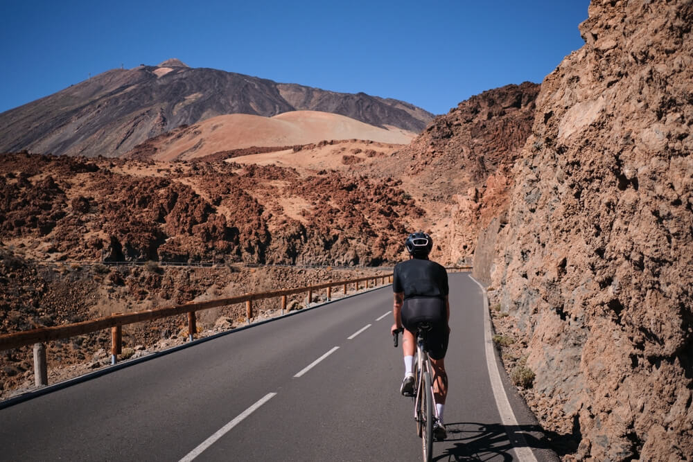 Radfahrer auf einer Straße im Teide Nationalpark mit dem Teide im Hintergrund.