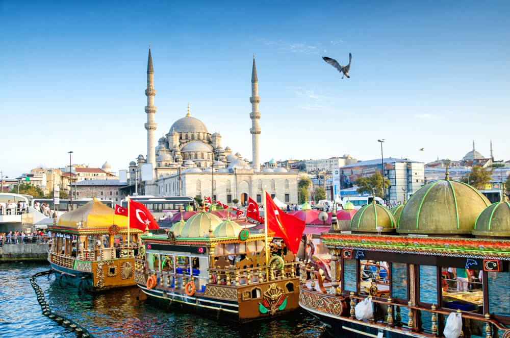 Bunte Schiffe auf dem Wasser mit Moschee im Hintergrund in Istanbul.