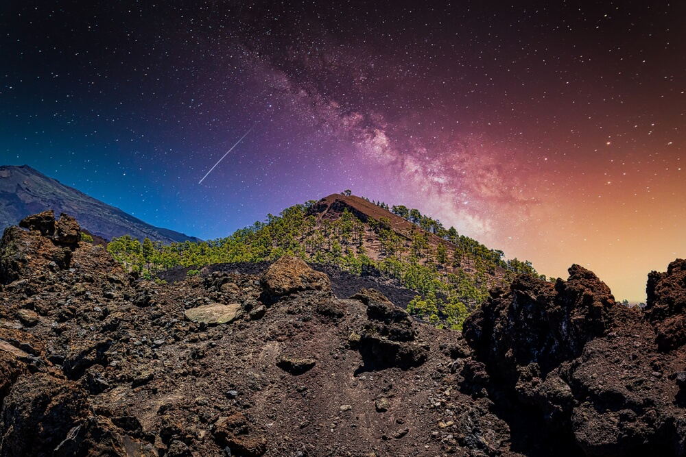 Stargazing in Tenerife: A purple and blue night sky with a shooting star over a volcano