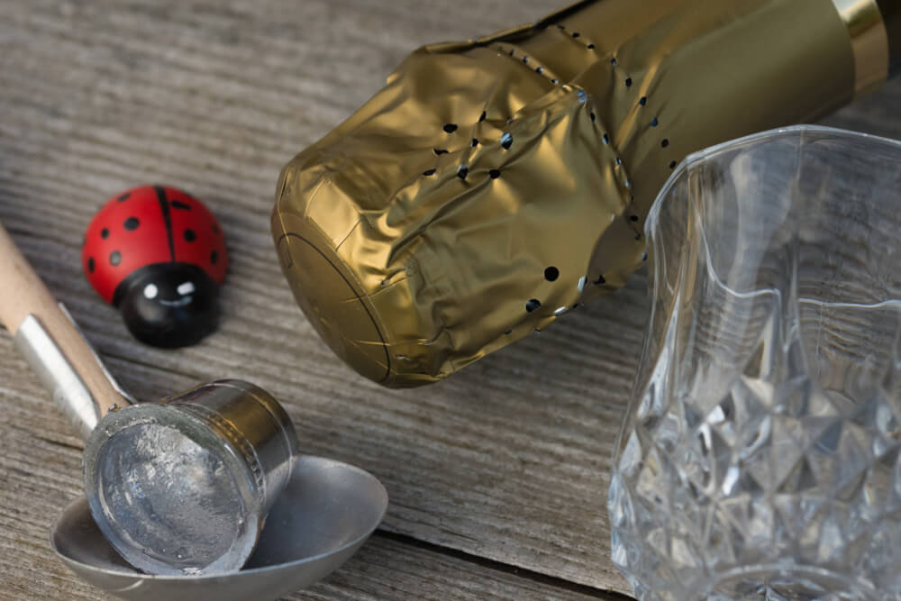 Bleigießen: a ladle with silver metal on top and a champagne bottle next to it