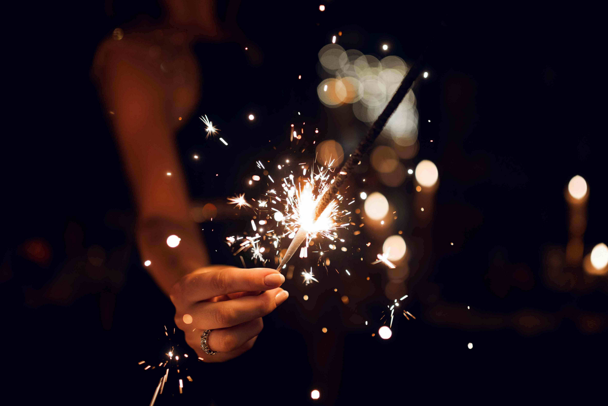 Strange New Year’s Traditions: Woman’s hand holding a sparkler in the dark