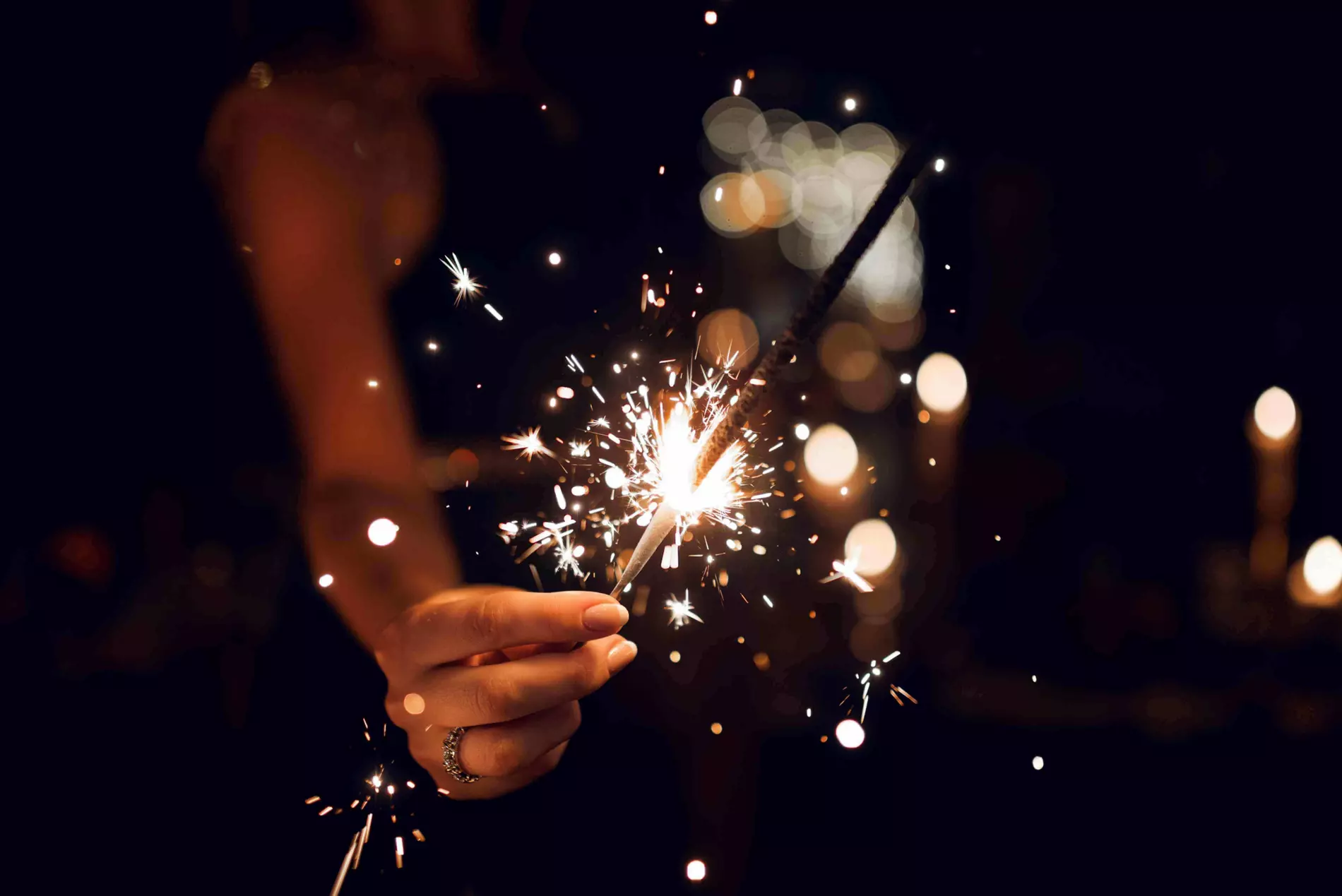 Strange New Year’s Traditions: Woman’s hand holding a sparkler in the dark