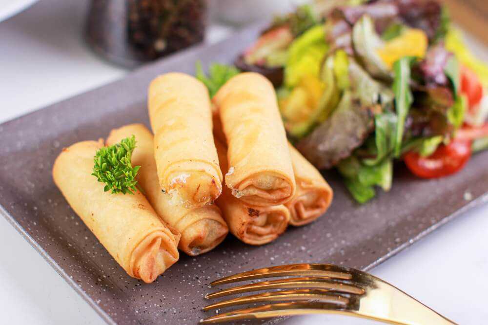 Short eats in Sri Lanka: A close-up of 6 spring rolls on a plate with salad
