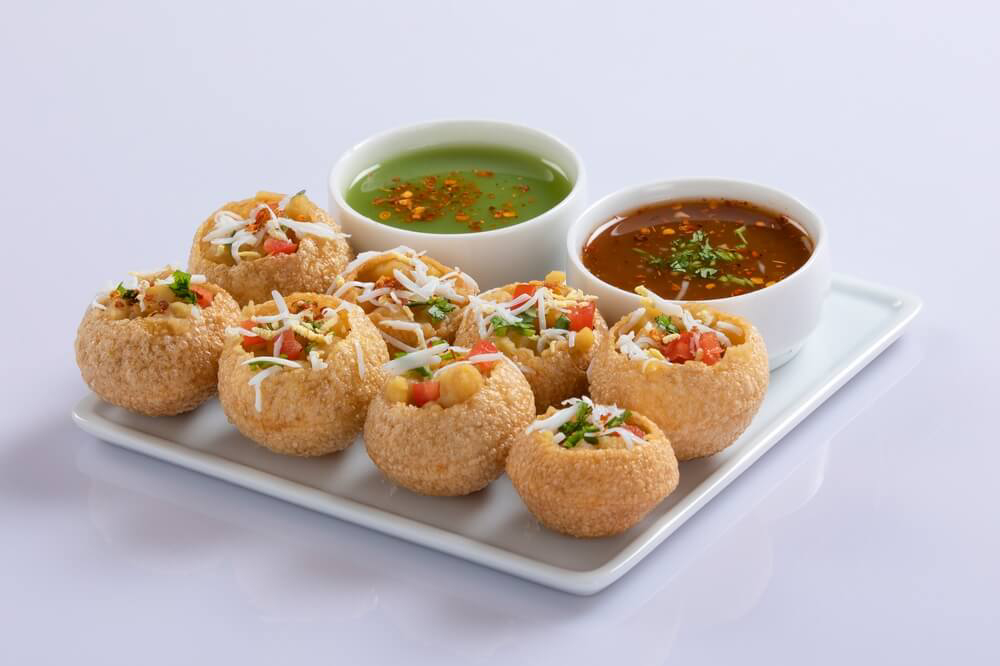 Sri Lankan lunch: 8 pani puris stuffed with vegetables served on a plate with green and red sauce