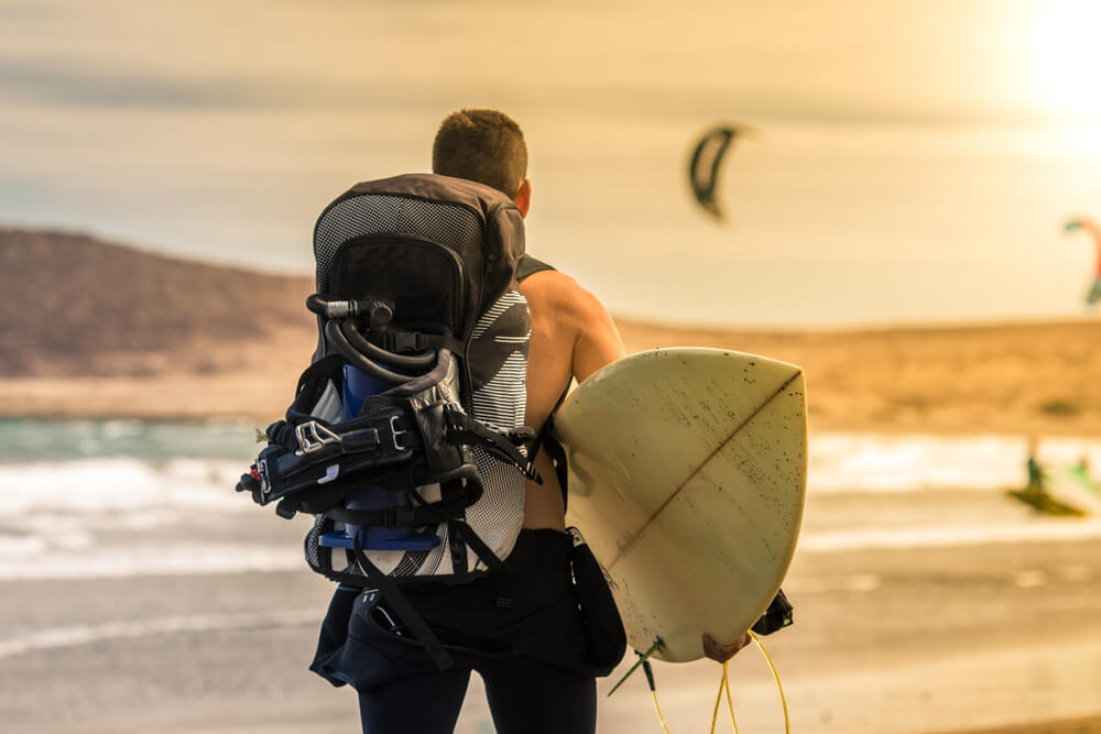 Surfen auf Teneriffa: Mann mit Surfbrett am Strand von El Médano