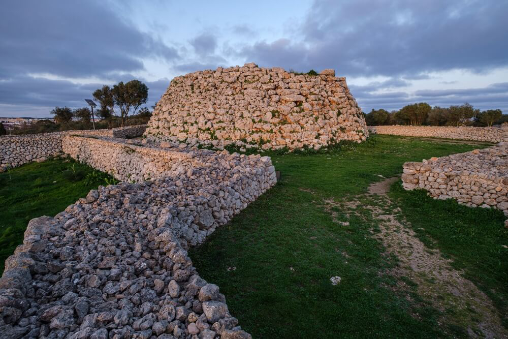 Talayot of Trepucó: a low lying stone structure and wall on grassland