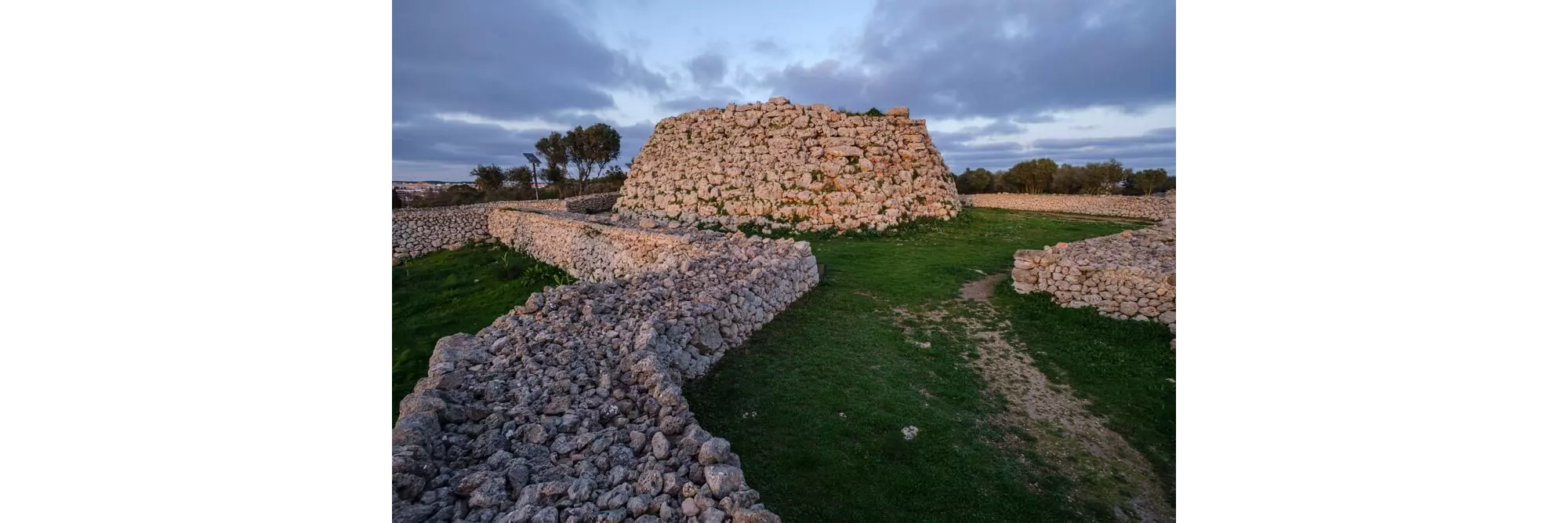 Talayot of Trepucó: a low lying stone structure and wall on grᴀssland