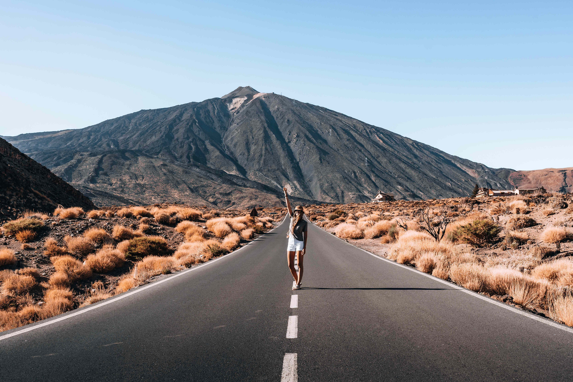 Teide National Park: A young woman standing in the middle of the road with El Teide behind