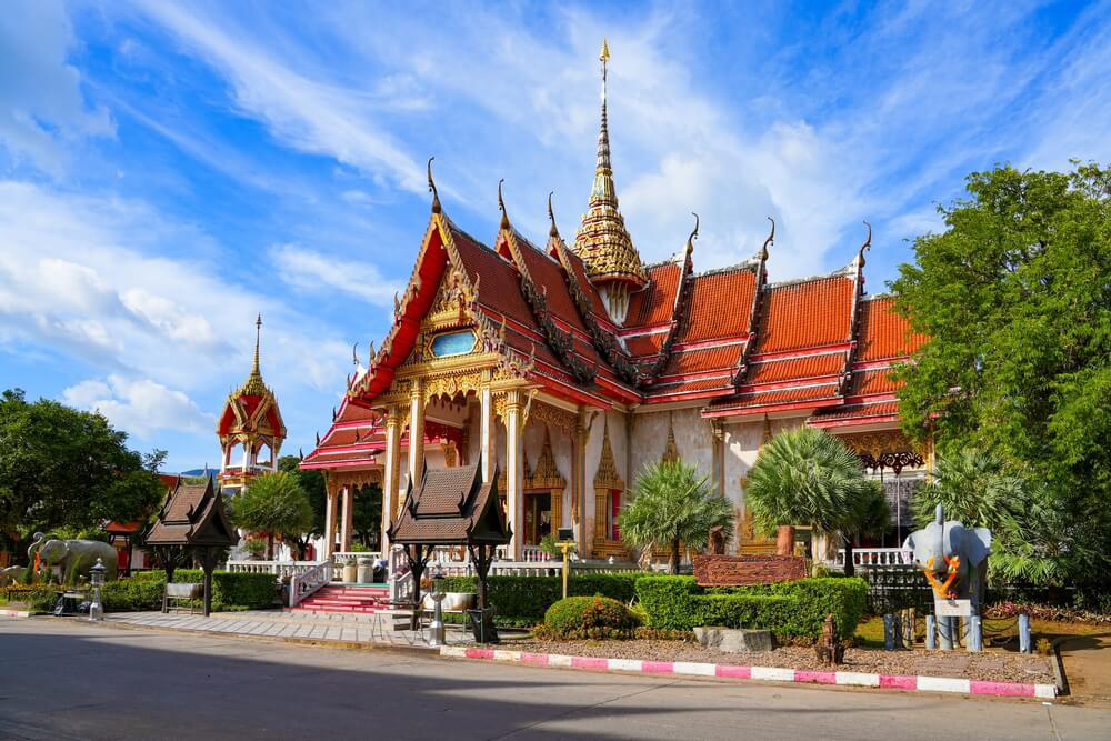 Wat Chalong: White temple with a red roof and elephant statues outside
