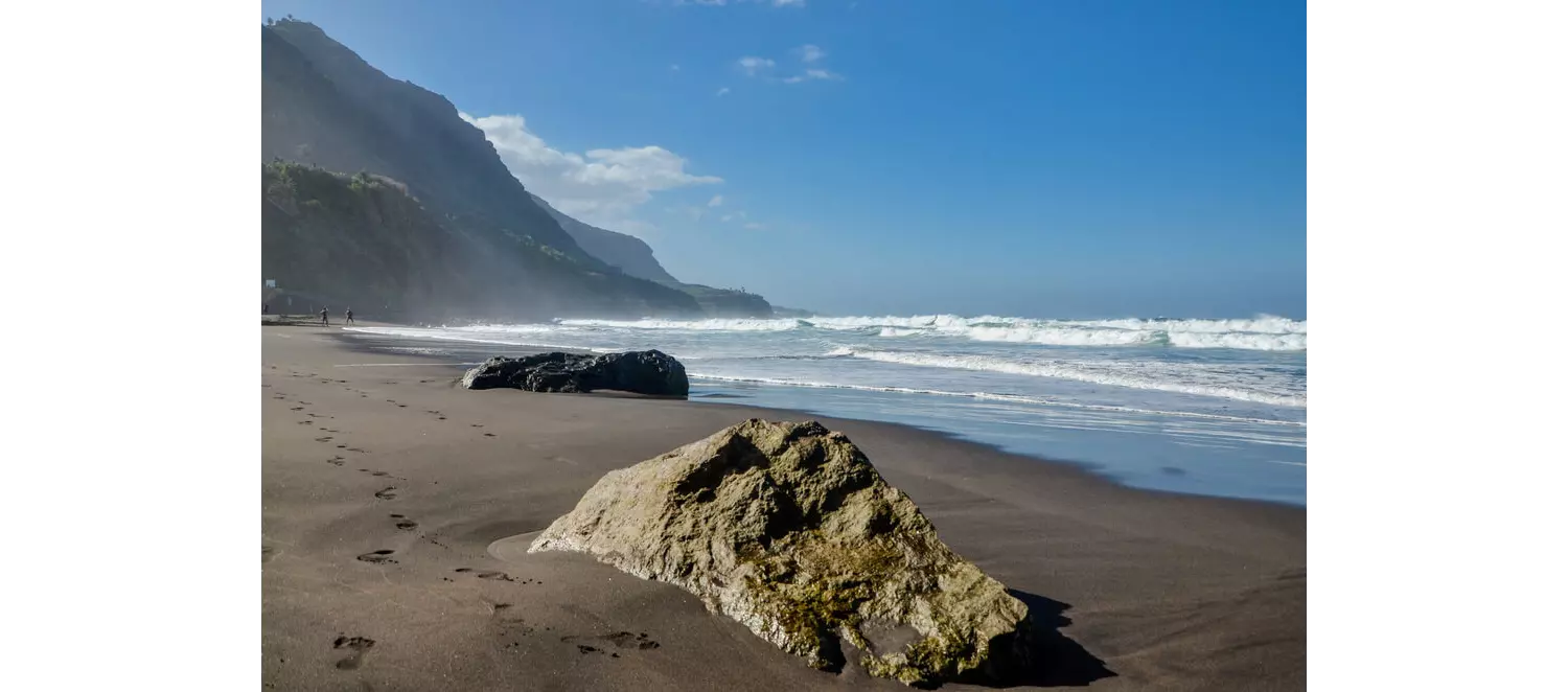 Naturbelassener schwarzer Strand mit Felsen auf Teneriffa.