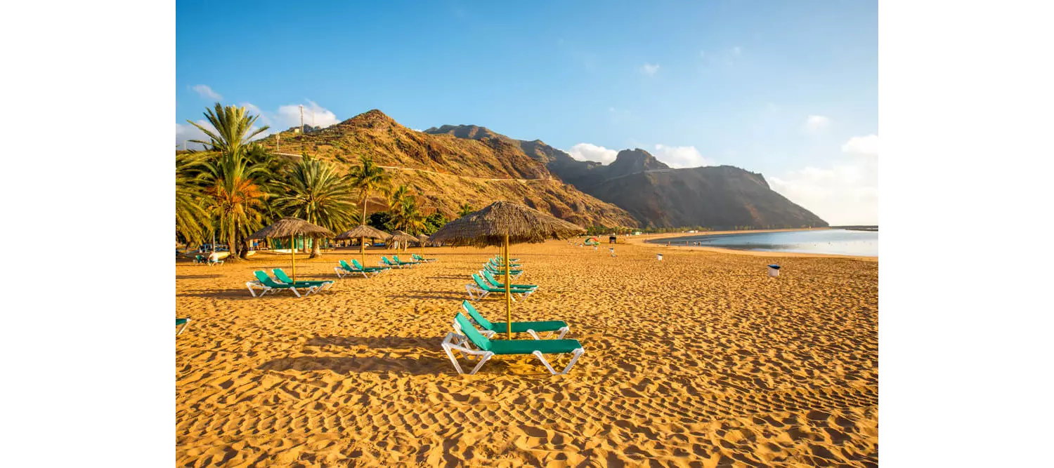 Goldgelber Strand mit Liegen und Palmen.