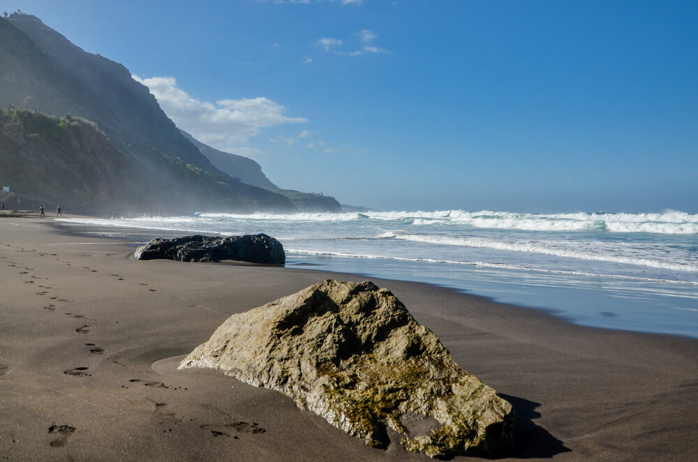 Naturbelassener schwarzer Strand mit Felsen auf Teneriffa.