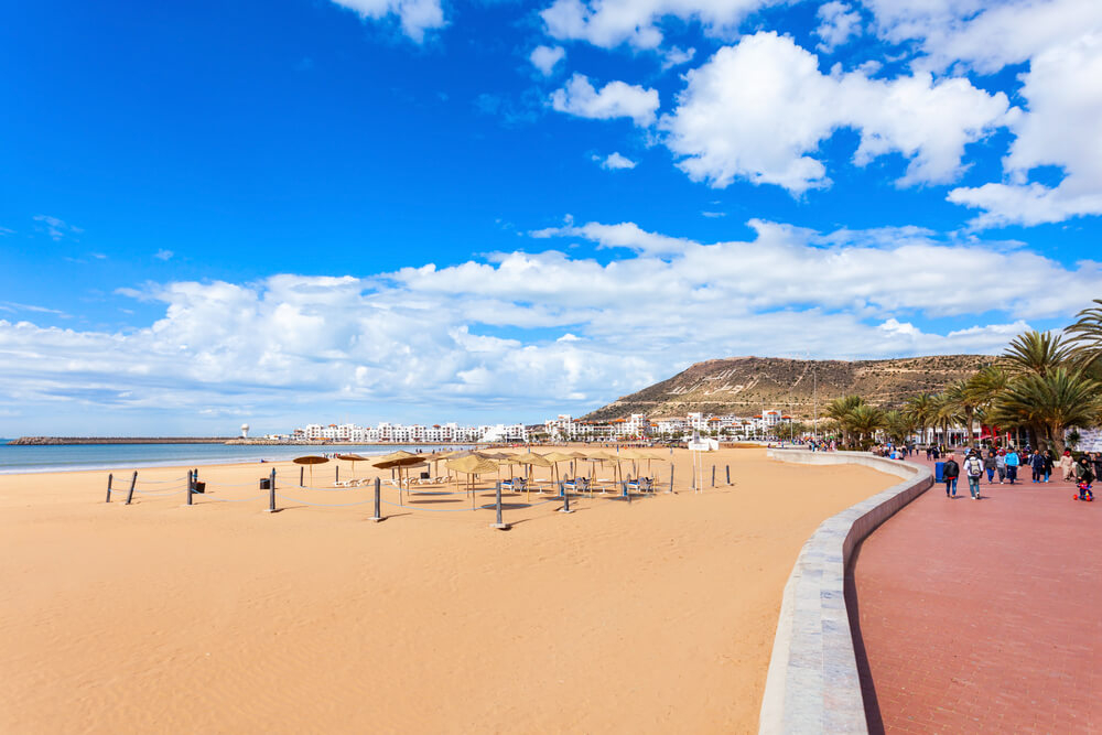 Things to do in Agadir: Agadir beach with a red promenade full of people