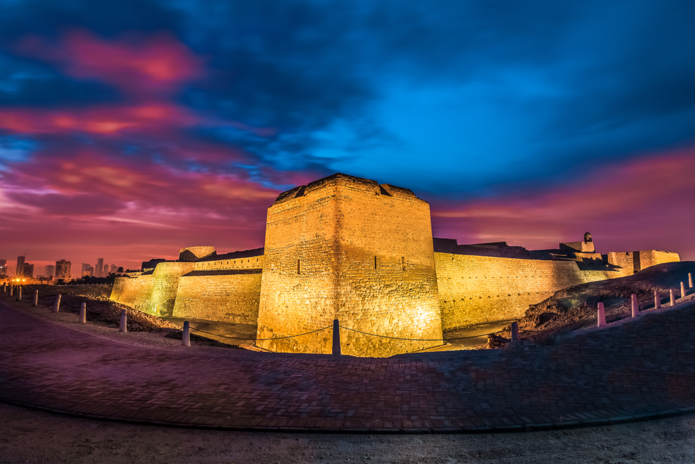 Bahrain Fort: The illuminated facade of the fort at sunset