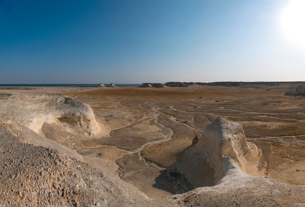 Hawar: Sandy, arid desert landscapes of Hawar with ocean in the distance 