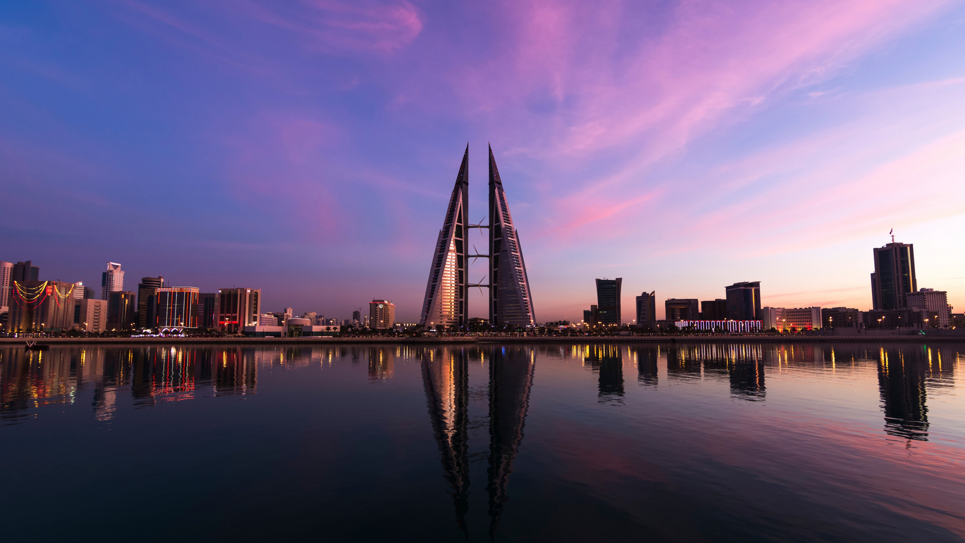 Things to do in Bahrain: Pink and purple sunset over the skyline of Bahrain
