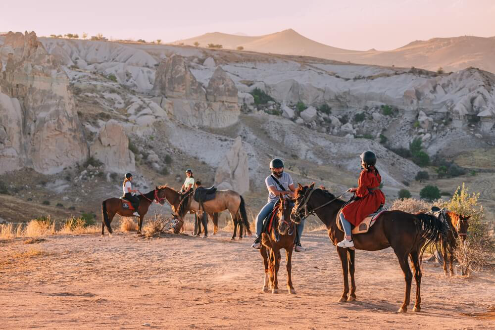 Places to see in Cappadocia: People riding through the Cappadocia mountains on horseback 