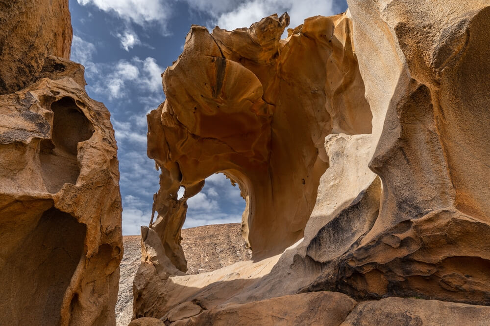 Things to do in Fuerteventura: Golden cliff faces carved by years of 