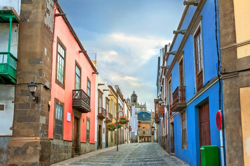 Things to do in Gran Canaria: Colourful buildings lining a black cobbled street of Vegueta