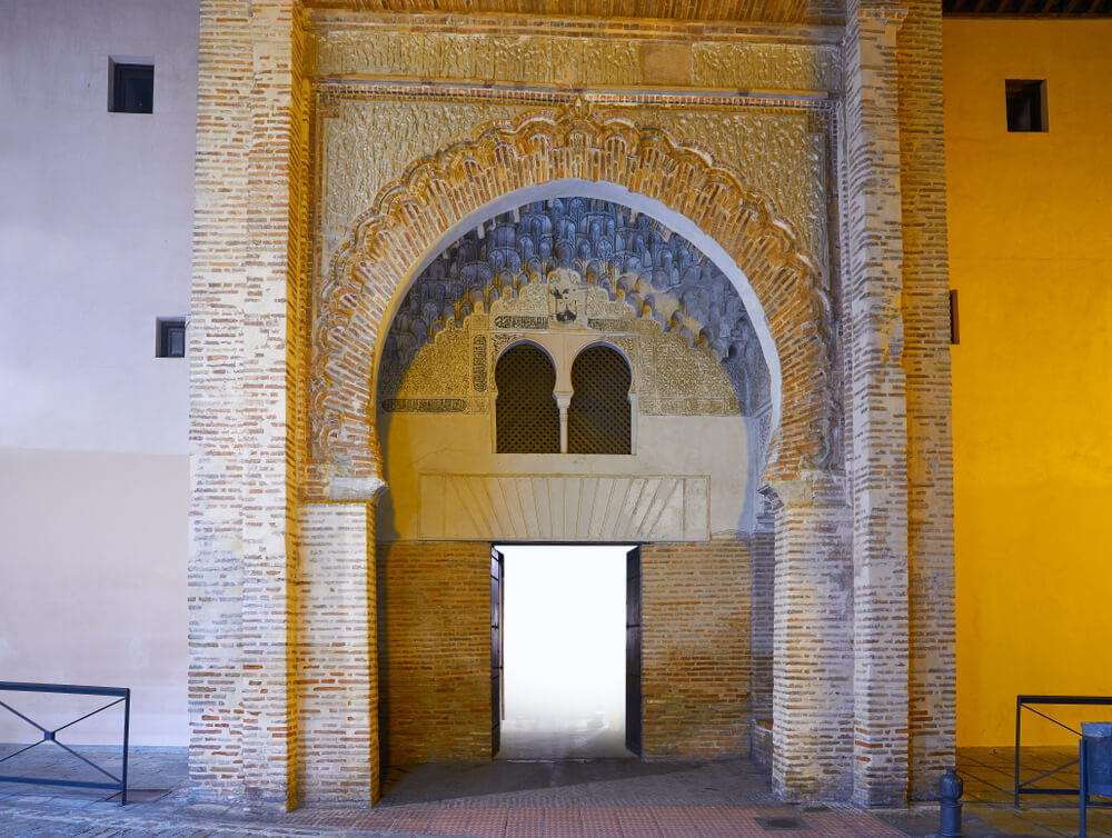 Corral del Carbón: A yellow building with a stone arched entrance 