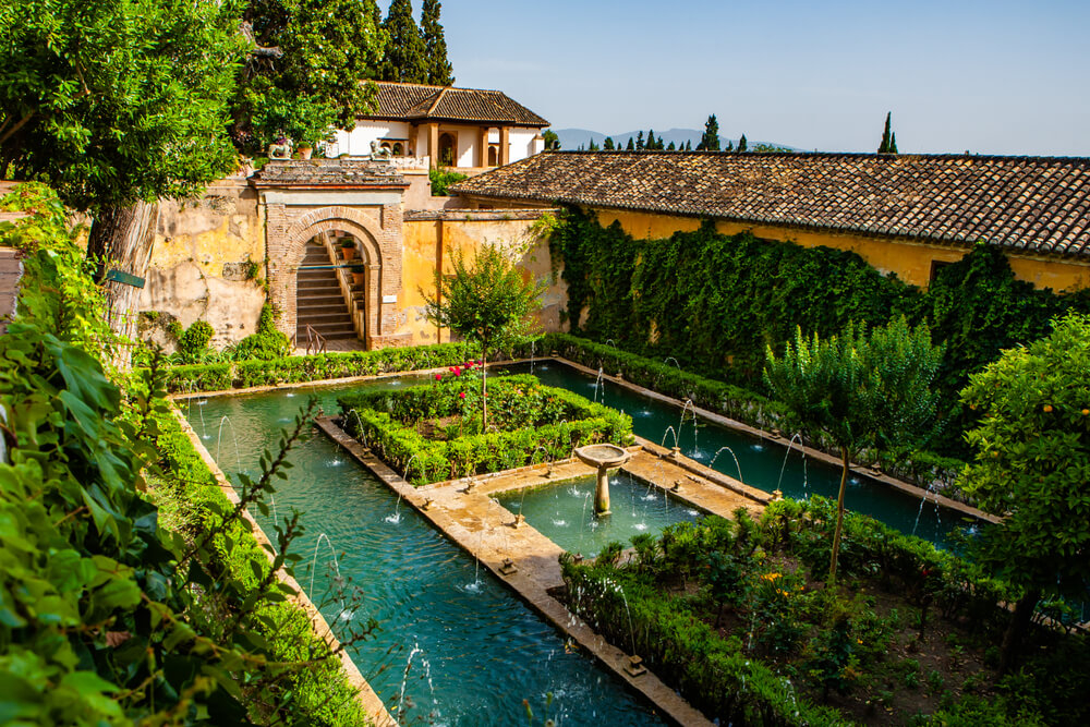 Things to do in Granada: A walled, patio garden with green shrubs and a pool
