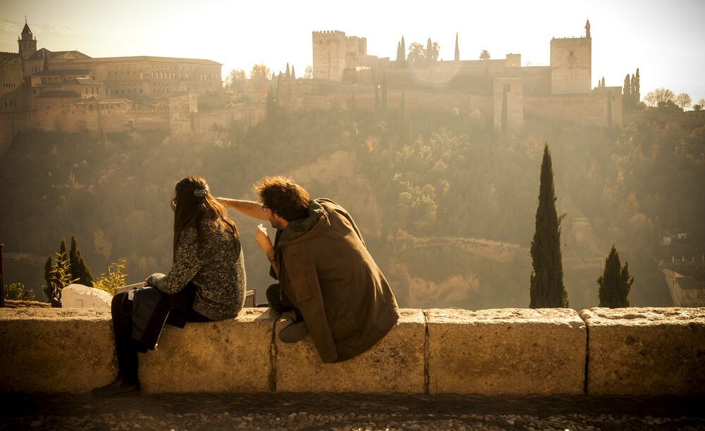 Mirador San Nicolás: A couple sitting on a stone wall looking out over the city